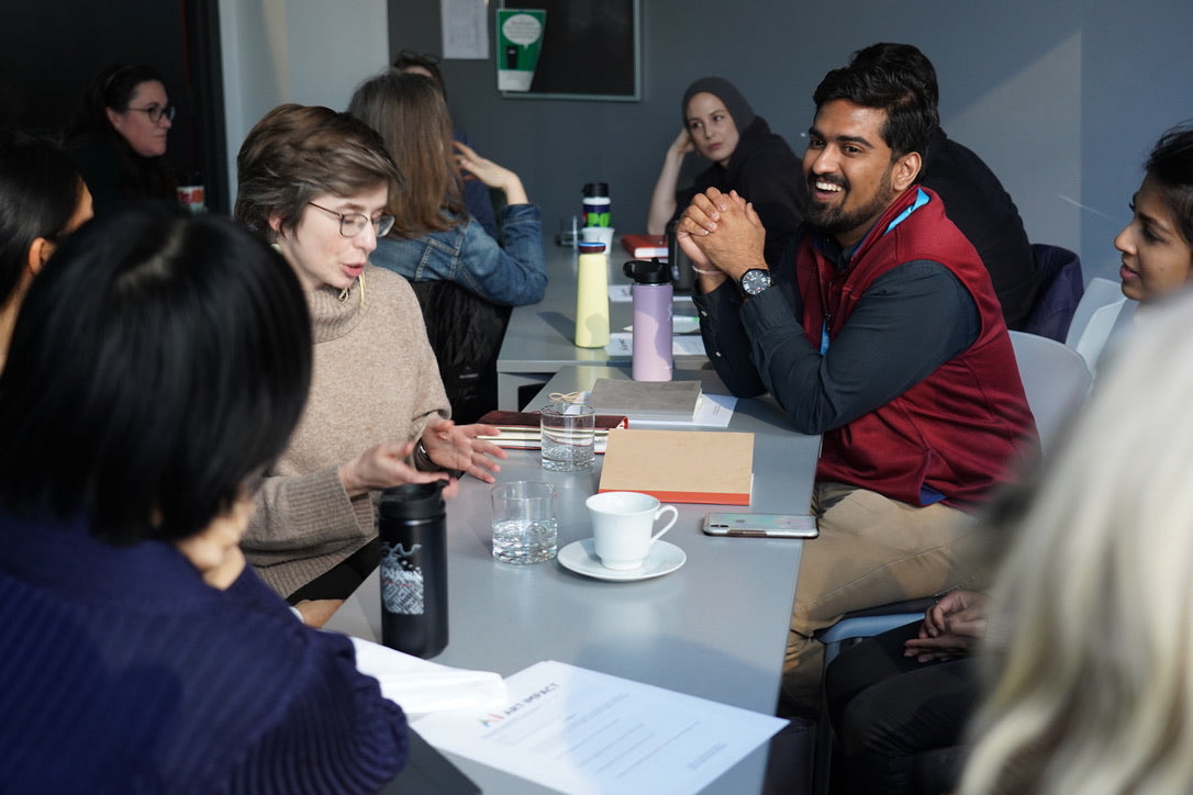 image of participants at Art Impact workshop in Vancounver at Simon Fraser University on February 28, 2020. Several participants are sitting around a table and discussing an issue heatedly.