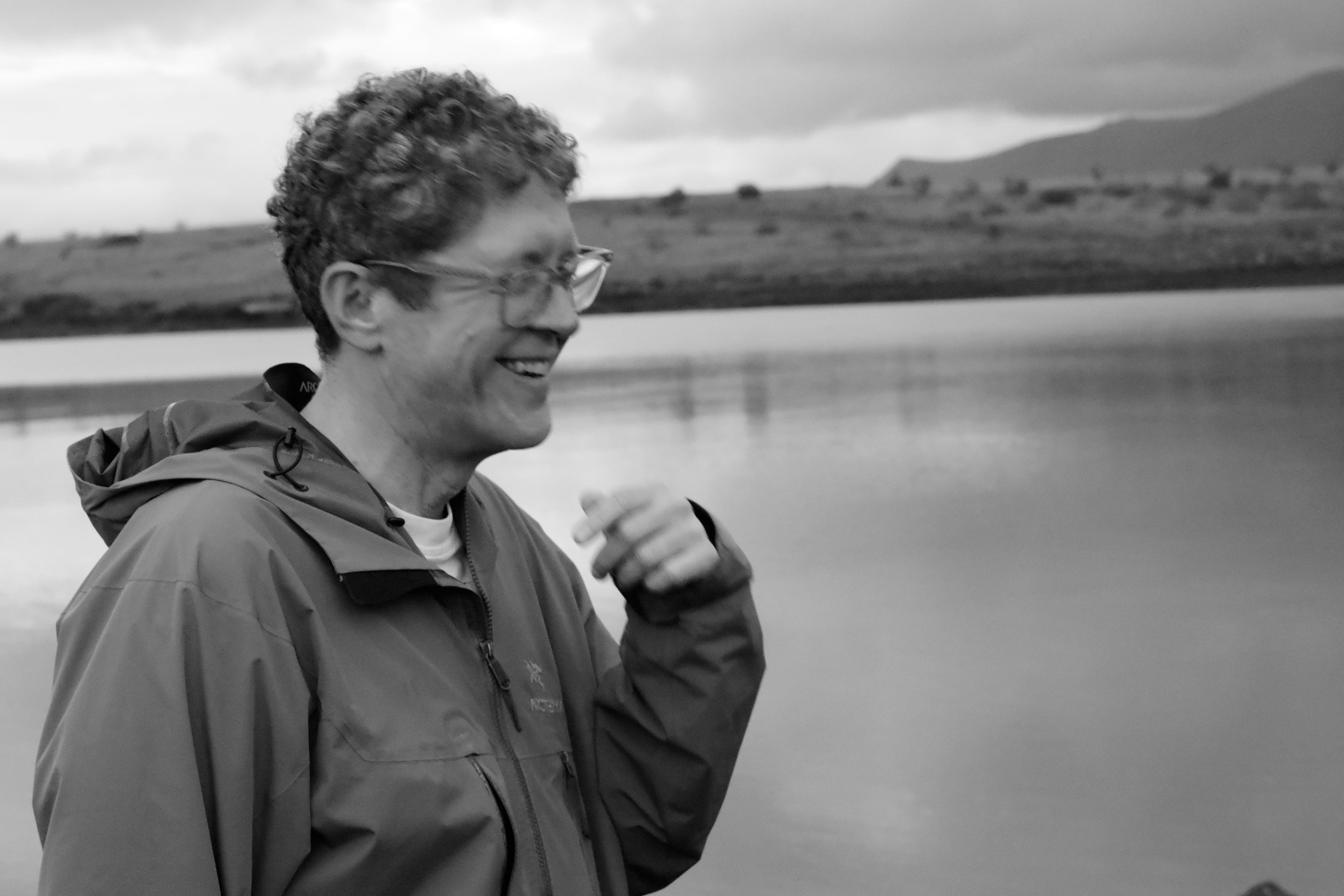 image of research director Jerrold McGrath, a 50-year-old white man wearing an Arcteryx jacket, with curly hair, laughing by the beach in Reykjavik, Iceland