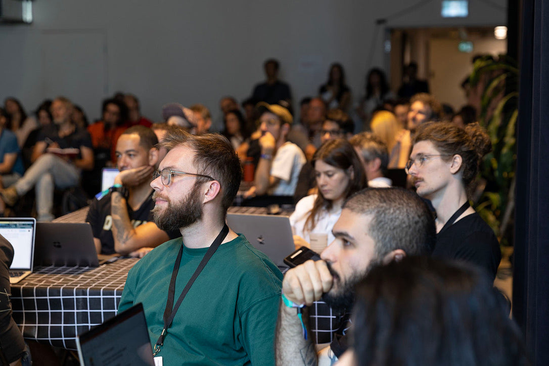 photograph of participants at MUTEK Forum in 2023 listening to speakers from UKAI. Around 100 people are seated at desks with laptops in front of them. The crowd is generally in their 20s.