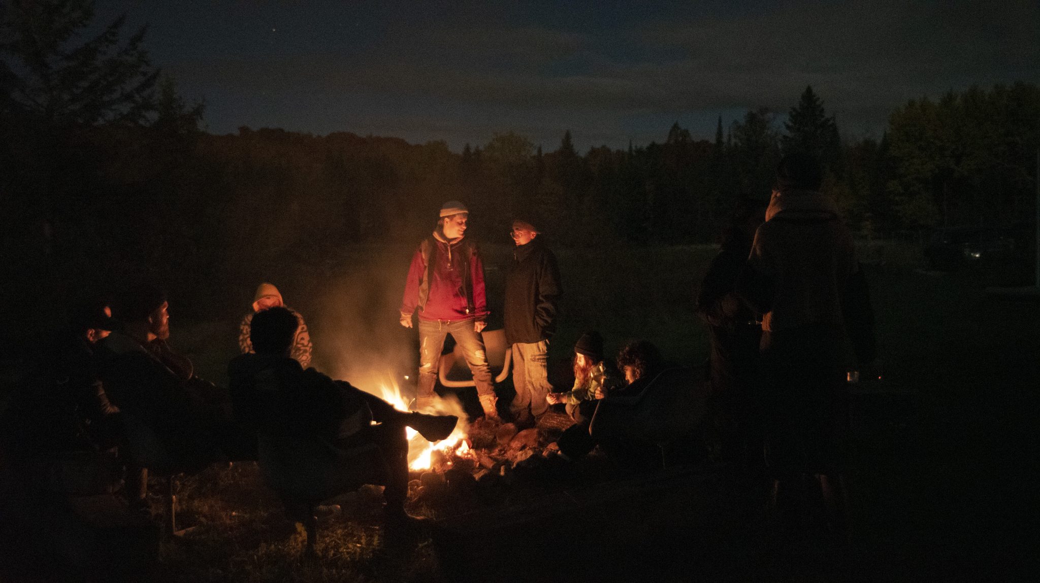 artists gathered around a fire at night during the residency