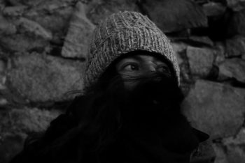 black and white photo of Time Travel Agency founder Jocelyn Ibarra with a scarf covering her mouth and a toque on her head